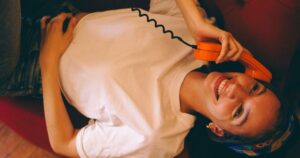 6 Things Someone With Psychopathic Traits Might Do When They First Meet You Young woman lying on sofa, talking on orange vintage phone with a cheerful smile.