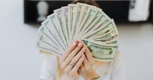 Are You Really Middle Class in 2026? These 6 Numbers Tell the Truth Close-up of hands holding a fan of US dollar bills, showcasing financial abundance.