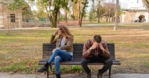 7 Phrases a Man Who Has Cheated on You Says — and What They Really Mean An upset couple seated on a park bench, expressing frustration during an autumn day.
