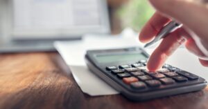 Financial accounting using calculator with laptop computer on desk, budget, audit or home finance management