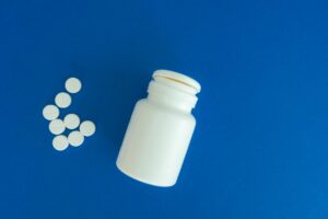 Scientists Finally Solved the Mystery Behind Statin Muscle Pain Flat lay of white pills and a container against blue backdrop, symbolizing healthcare.