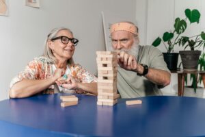 Senior man and woman playing Jenga, creating a fun and engaging atmosphere indoors.