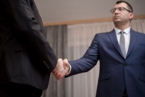 Trump Bought Dell Stock Months Before Pentagon Handed It a $9.7B Contract Two businessmen in formal attire shaking hands during a meeting.
