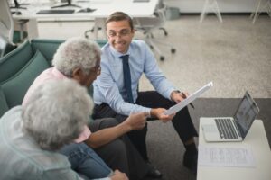 Congress Is Pushing to End Federal Taxes on Social Security — Here's Where It Stands Consultant discussing financial plans with senior clients in a modern office setting, using documents and a laptop.