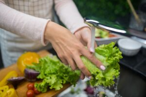 When 'Clean Eating' Becomes an Obsession: The Risks No One Talks About Hands washing fresh lettuce under running water. Healthy food preparation in home kitchen.