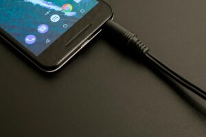 This Nightly Phone Habit Is Putting Your Home at Real Fire Risk Close-up of a smartphone being charged, displaying a modern interface on a dark backdrop.