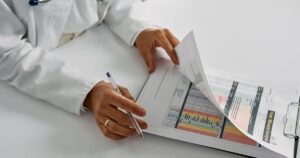 A medical professional checking patient reports with a clipboard in an office setting.