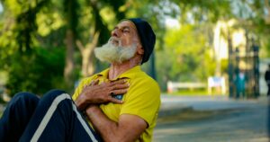Elderly man performing sit-ups in a sunny park, promoting senior fitness and wellness.