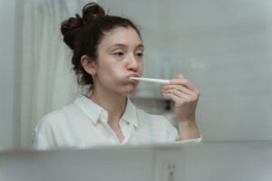 Side view of a woman brushing her teeth, focusing on dental care and hygiene.