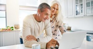 Trump's New 401(k) Rules: What People in Their 50s Need to Know Middle aged couple using laptop in their home. Financial planning concept