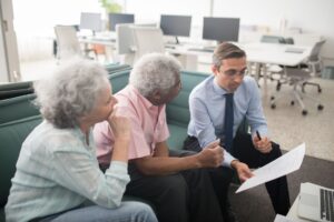 New Laws in Congress Could Mean Bigger Social Security Checks for Millions Business professional consults elderly clients in an office setting. Collaborative discussion, paperwork visible.