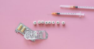 Could a Piece of Chocolate Replace Your Daily Insulin Injection? Flat lay of diabetes medication symbolized with pills and syringes on a pink background.