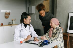 New Medicaid Changes Under Trump Administration Raise Concerns for Seriously Ill Patients A doctor consulting with cancer patient and friend at home, offering support.