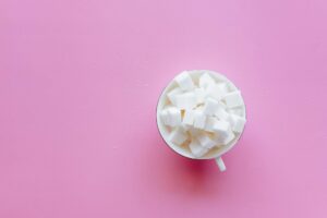 Top view of a cup filled with sugar cubes on a vibrant pink background.