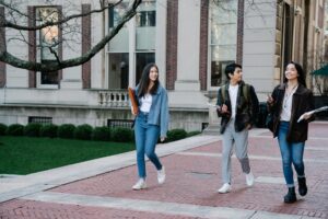 Barron Trump’s NYU College Experience: Secret Service, Video Games, and a “Ghostly” Presence Group of young students walking on campus sidewalk on a bright day, showcasing casual university life.