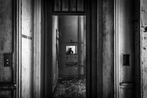 Why Do People 'See Ghosts'? A Psychologist Reveals 3 Real Reasons Creepy abandoned hallway with a reflection in the mirror, invoking intrigue and mystery.