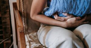 7 Signs of Ulcerative Colitis — and Why a New Clinical Study Matters Crop unrecognizable female touching belly while having acute pain in stomach sitting on couch