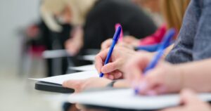 Students Schools Are Ditching Screens for Pen and Paper — Here's What's Happening Students taking notes using pen and paper