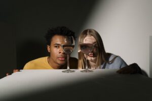 Famous Podcaster, Stephen Bartlett, Says Just a Couple of Glasses of Wine 'Ruined Days of His Life.' Is There Any Truth Behind the Viral Claim? Portraits of a diverse couple with creative reflections through wine glasses in a studio setting.