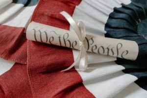 Trump's Attempt to End Birthright Citizenship Reaches the Supreme Court Close-up of a 'We the People' scroll on an American flag cloth background.