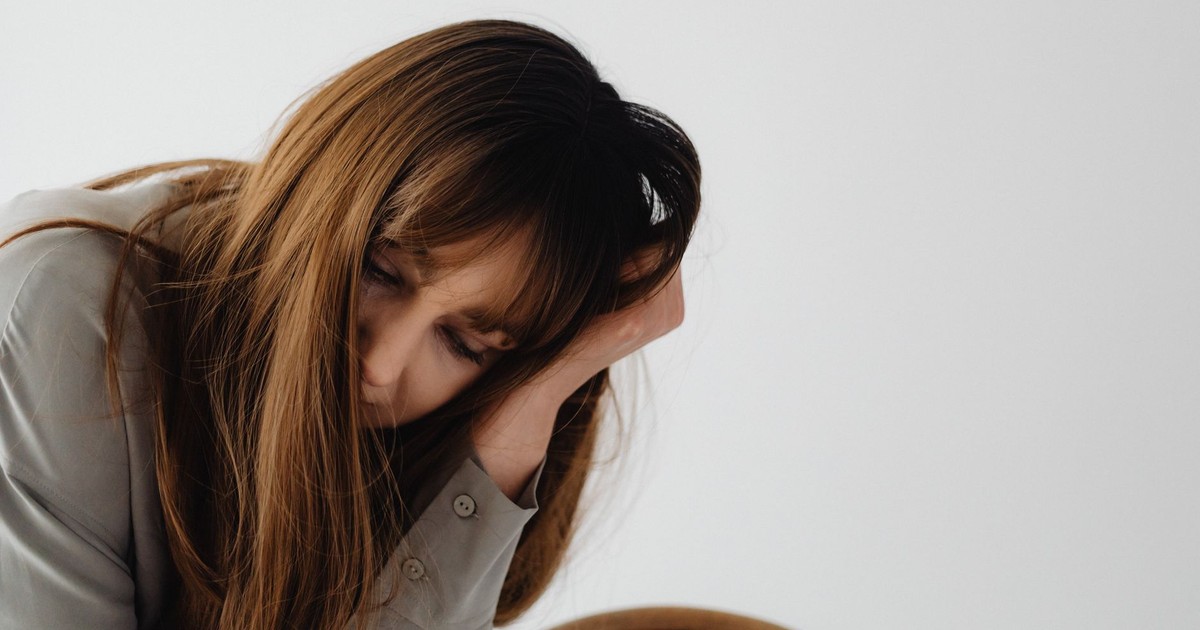 A contemplative woman rests her head in her hand indoors, depicting a moment of reflection and introspection.