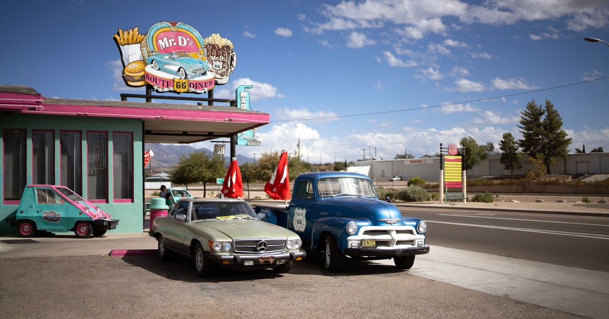 Vintage cars parked outside Mr. D's Route 66 Diner under a bright blue sky.