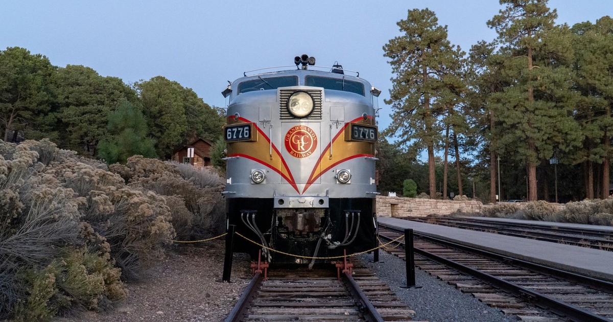 A classic train engine parked at Grand Canyon Railway surrounded by forest trees.