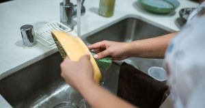 10 Things in Your Home That Are Dirtier Than Your Toilet Seat Close-up of hands washing dishes in a kitchen sink with running water.