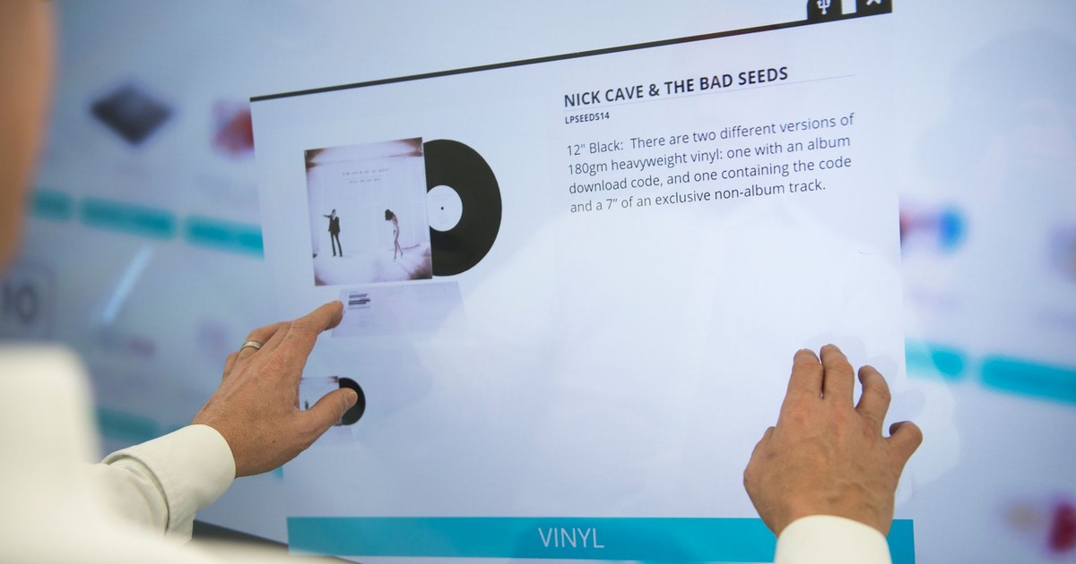 A person using a touchscreen to browse vinyl record information for Nick Cave & The Bad Seeds.