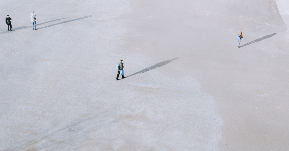 Minimalist aerial shot of four people spaced apart on a wide open area in Istanbul, creating long shadows.
