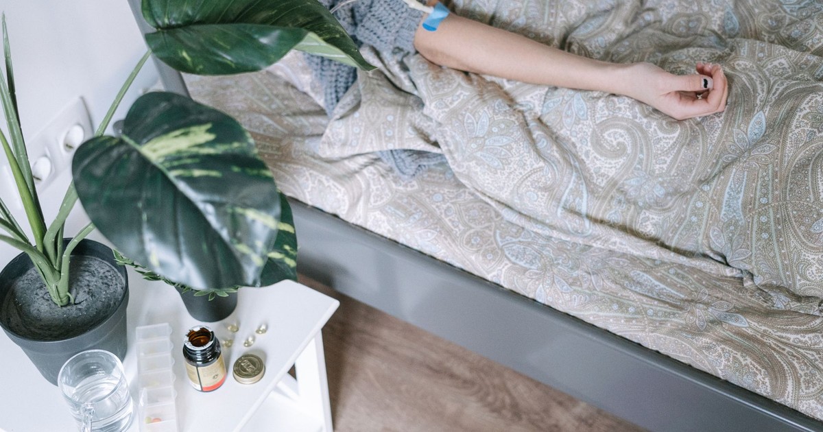 Close-up of a patient resting, surrounded by medicinal items and a bedside plant.
