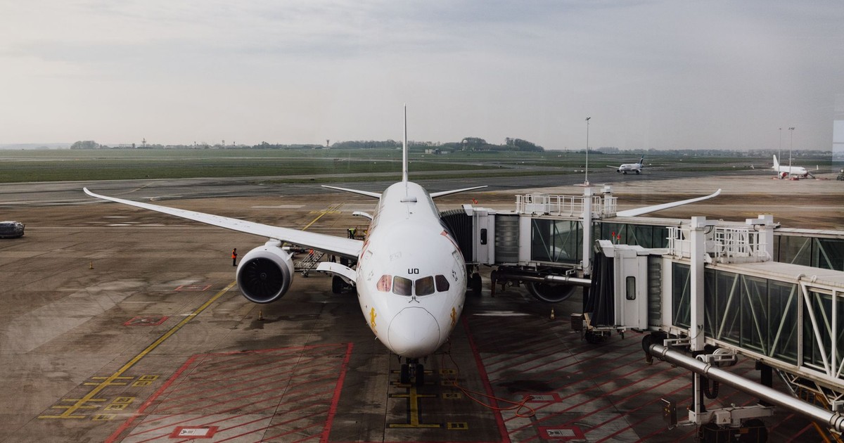 A modern jet airplane docked at an airport terminal gate, ready for boarding on a cloudy day.