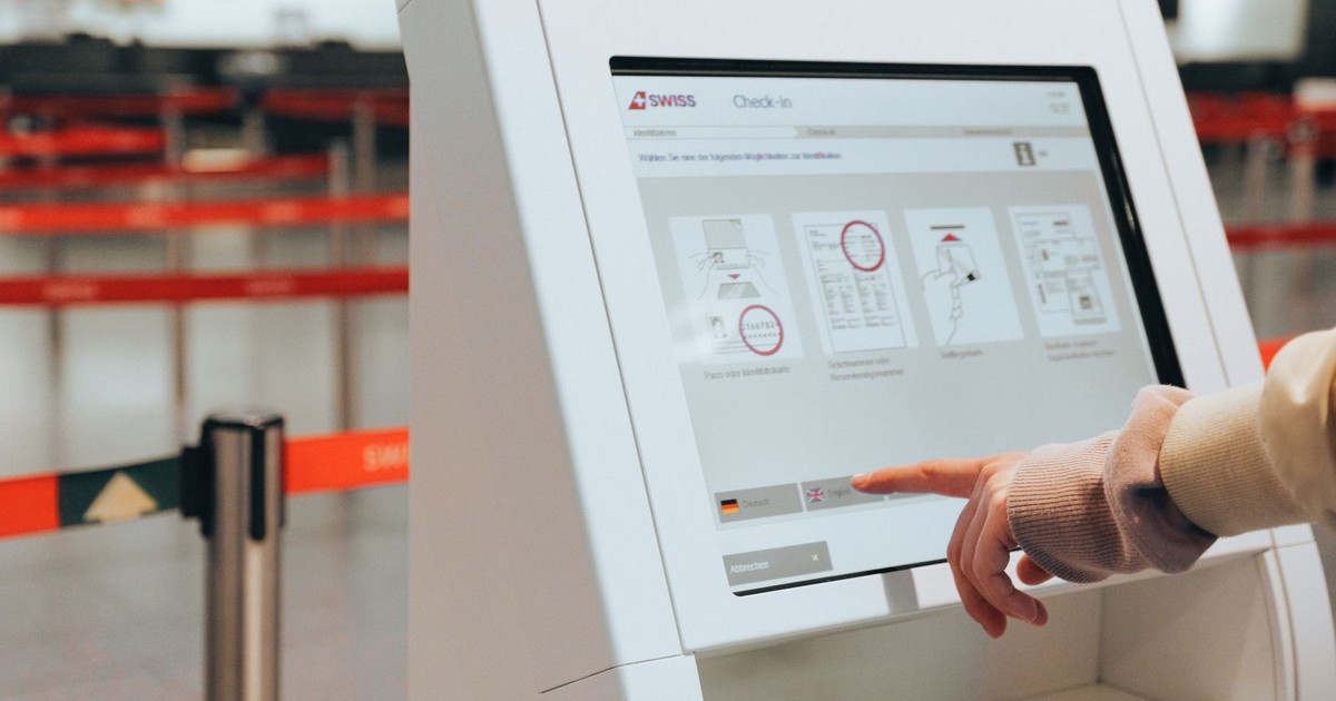 Passenger using self-service check-in kiosk at airport for convenient travel experience.
