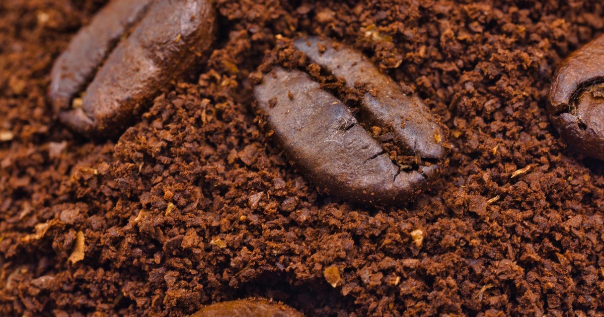 Macro shot of roasted coffee beans nestled in rich ground coffee, showcasing texture and aroma.
