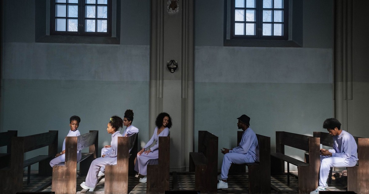 Group of choir members seated in church pews with soft daylight through windows creating a serene ambiance.