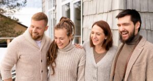 7 Daily Habits of Naturally Happy People Four friends laughing and bonding outdoors in a cozy winter setting.