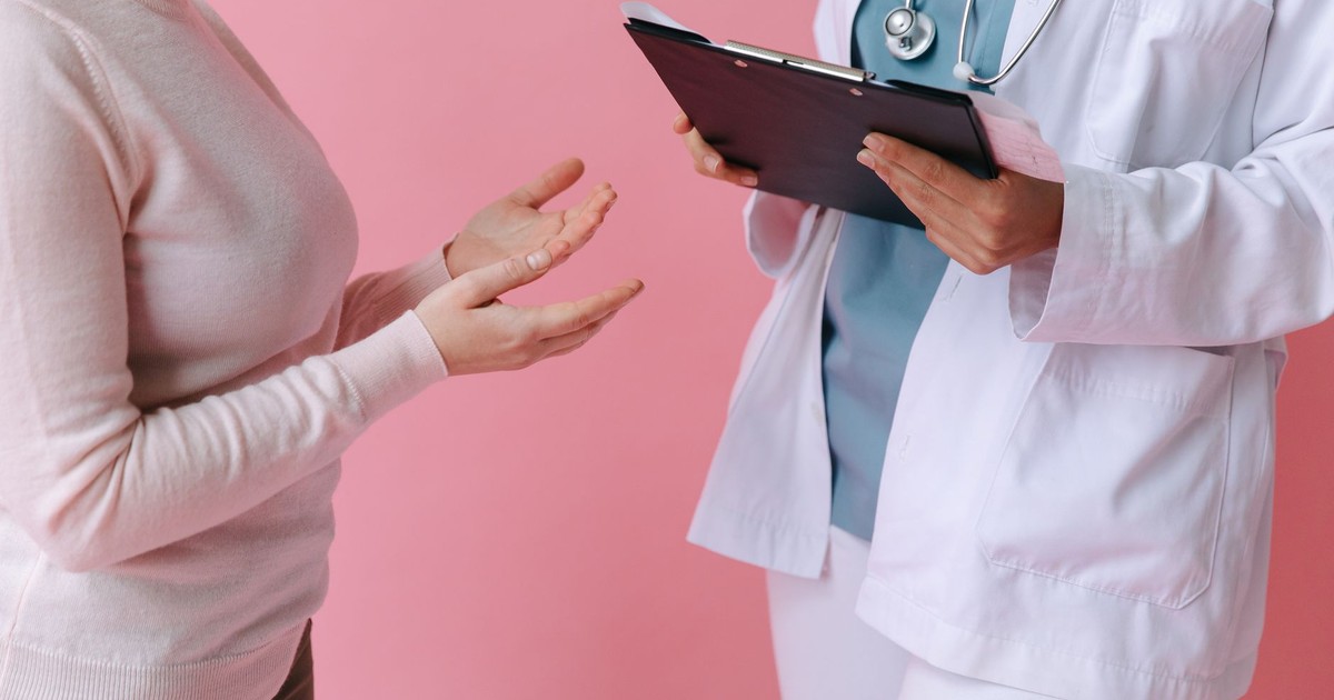 Close-up of a patient consulting a doctor with a clipboard in a medical setting.