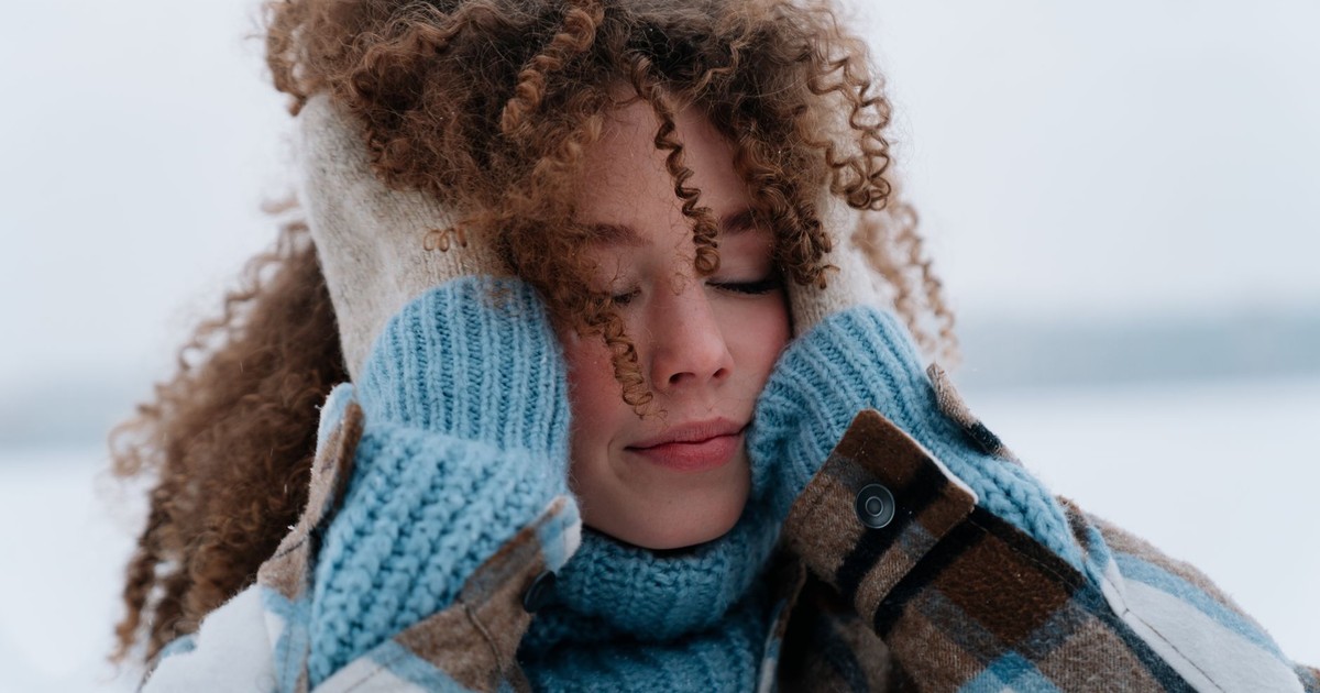 Portrait of a woman with curly hair enjoying winter outdoors with warm clothing.