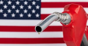 Gas dripping from fuel nozzle with American flag. Gasoline shortage, price and ethanol concept.