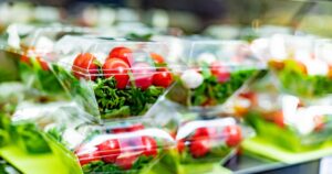 Pre-packaged vegetable salads displayed in a commercial refrigerator