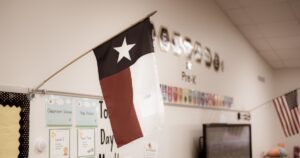 Texas and American flags proudly display in pre-kindergarten classroom near Dallas, modern preschooler class furniture, bulletin board, well organized school supply. Childhood education background