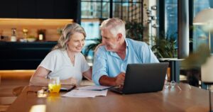 Documents, retirement and laptop with old couple at home for social security benefits, annuity growth and pension fund. Account balance, online banking and 401k withdrawal with people and profit