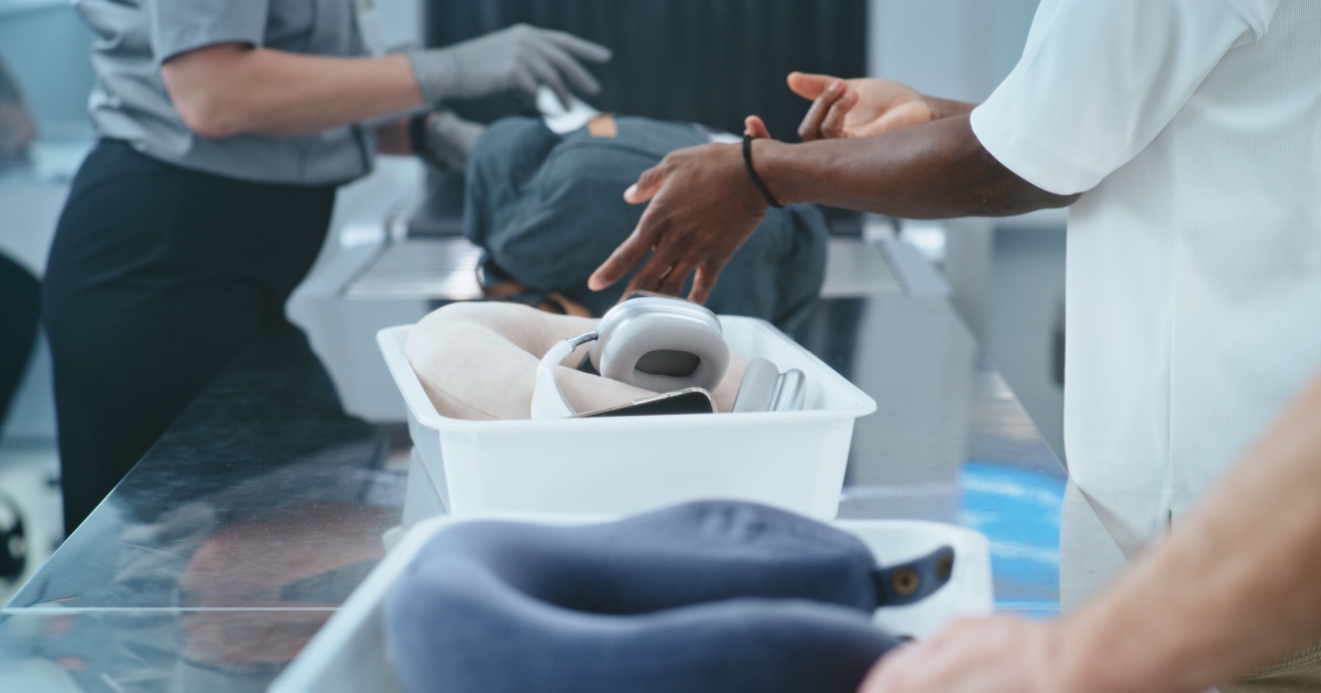 Security Checkpoint in Airport: Multiethnic People, Tourists Putting Personal Items, Bags in Trays for Metal Detector X-ray Scanning. Security Officer Controlling TSA Screening Procedures. Close Up.