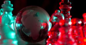 Crystal planet Earth amidst chess pieces showing the African continent, representing concepts of geopolitics, global power, competition for control, international relations, world leaders, struggle fo