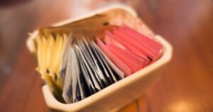 close up the selective focus of different colored and different types of sugar packets in the ceramic container