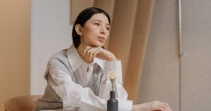 Researchers May Call You a 'mutant' if You're 1 in 10 People Who Have Unusual Personality Trait Combinations Thoughtful woman in white blouse and vest sitting at a table indoors, lost in deep thought.
