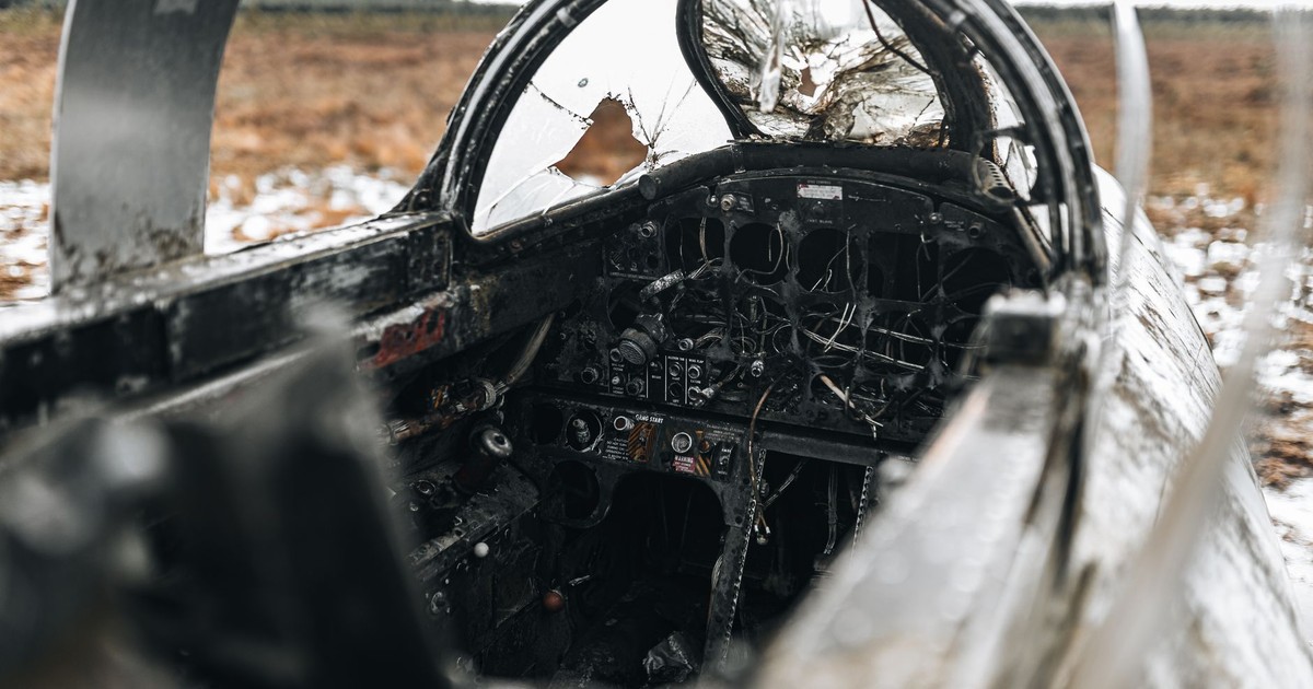 A close-up view of a destroyed cockpit in an abandoned aircraft wreckage in a snowy field.