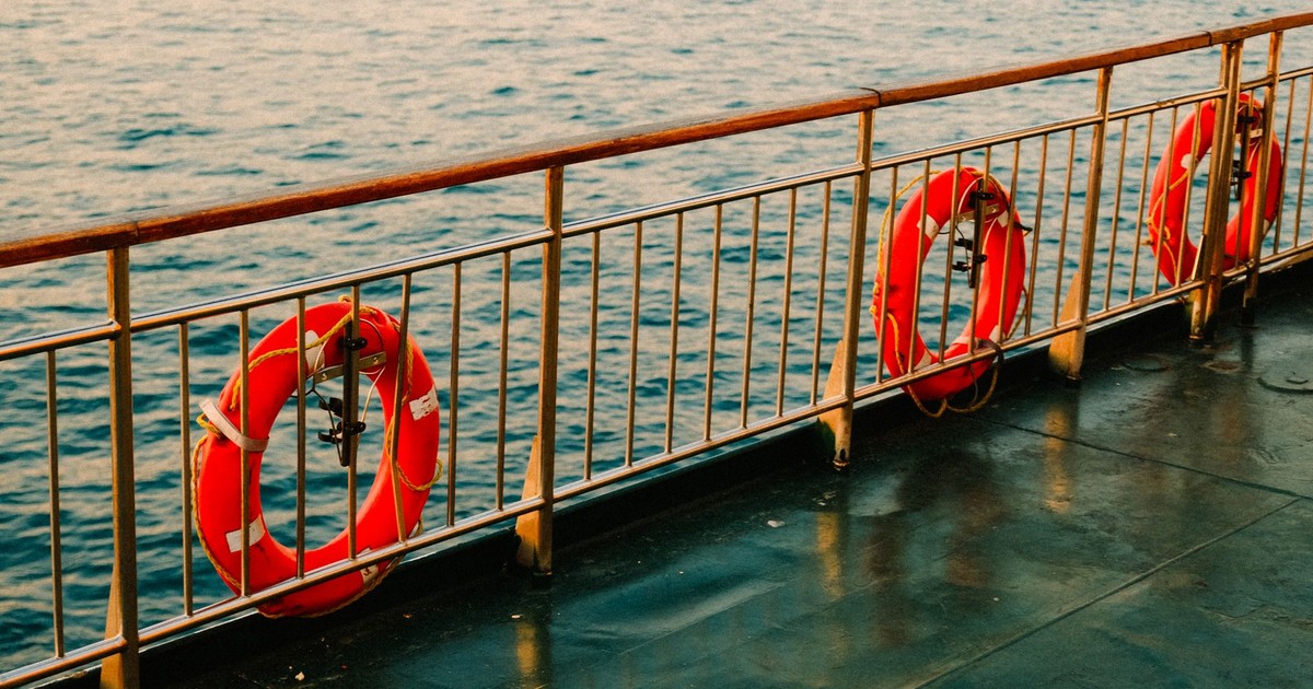 View of ship deck with lifebuoys and calm sea, capturing serene ocean travel.