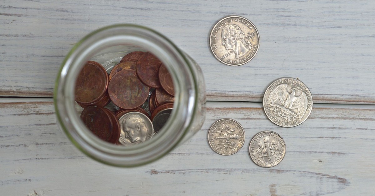 Top view of a jar filled with coins placed on a wooden table, depicting savings.