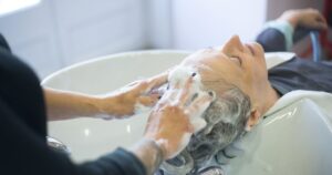 Close-up of senior woman getting hair washed with foam at salon sink, enjoying the pampering session.